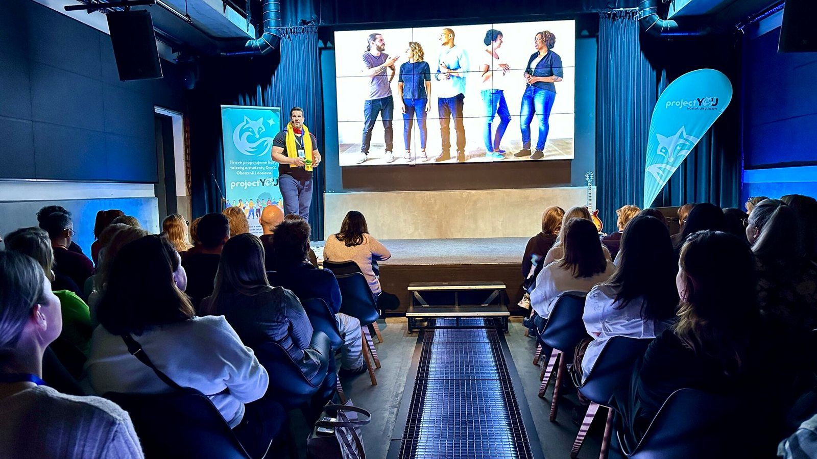 A speaker presenting on stage at a projectYOU event